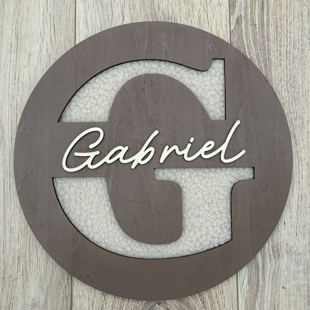 Plaque de porte ronde en bois taupe, initiale G sur fond bouclette et prenom Gabriel en relief